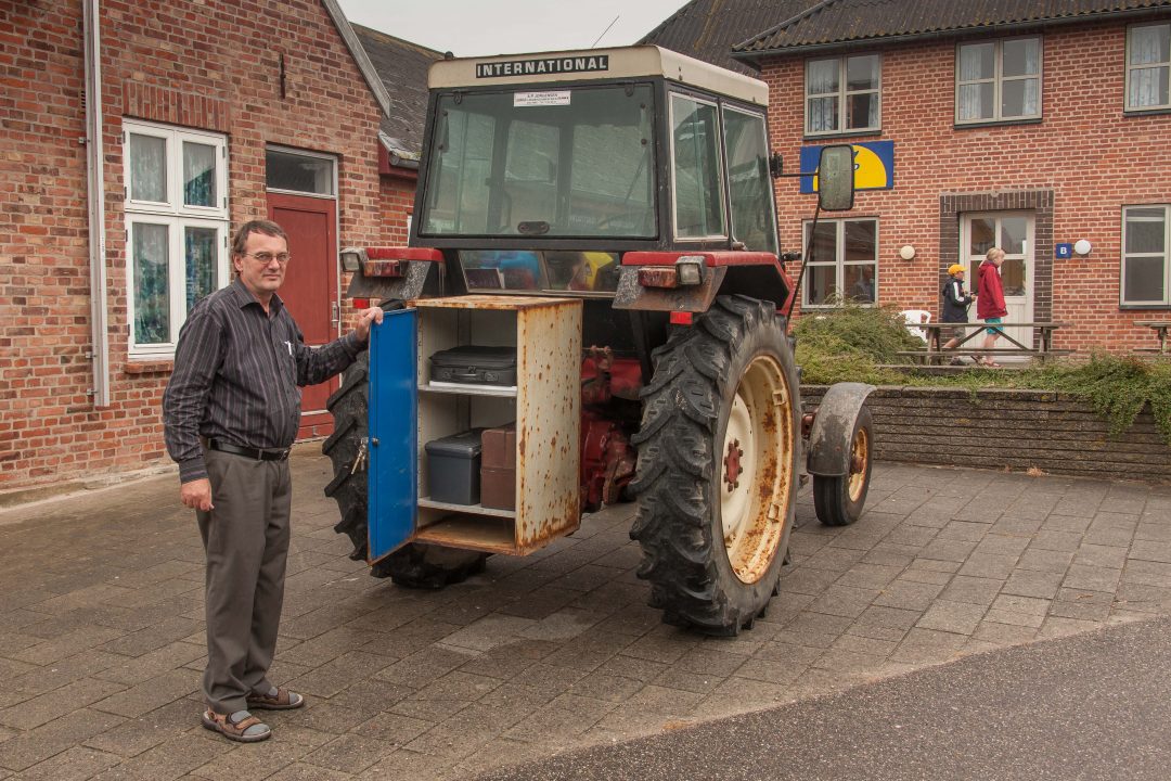 Palle Rjaberg bij zijn tractor met achterop een kist voor tas en medicijnen.